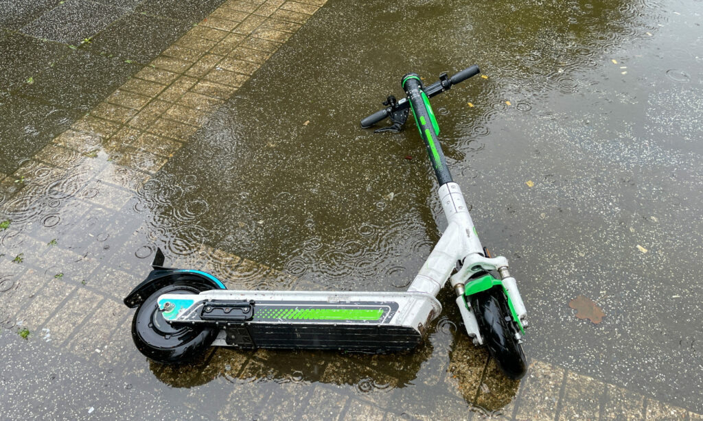 Electric scooter abandoned in water in puddle.