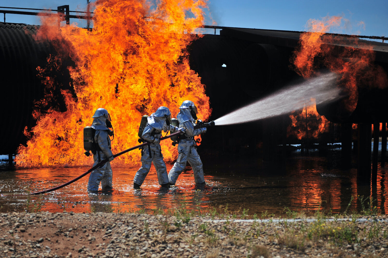 U.S. Air Force firefighters with the 27th Special Operations Civil Engineer Squadron work to extinguish a simulated engine fire at Cannon Air Force Base, N.M., Aug. 2, 2012.More: Cannon firefighters coordinated with the local fire department and practiced functioning under pressure. (DoD photo by Airman 1st Class Eboni Reece, U.S. Air Force/Released). Original public domain image from Flickr