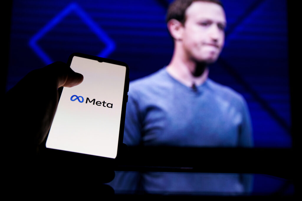 Meta logo on screen and Mark Zuckerberg is a Chief Executive Officer of Metaverse in background